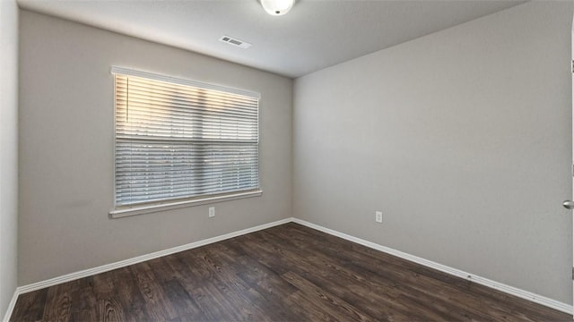 unfurnished room with visible vents, baseboards, and dark wood-style flooring