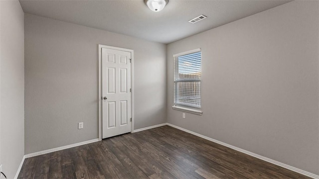 empty room featuring dark wood finished floors, baseboards, and visible vents