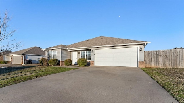 ranch-style home featuring a front lawn, fence, concrete driveway, an attached garage, and brick siding