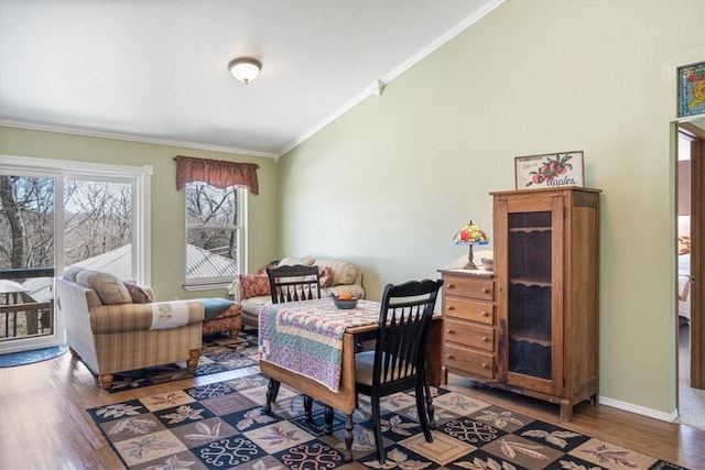 dining space featuring wood finished floors, lofted ceiling, baseboards, and ornamental molding