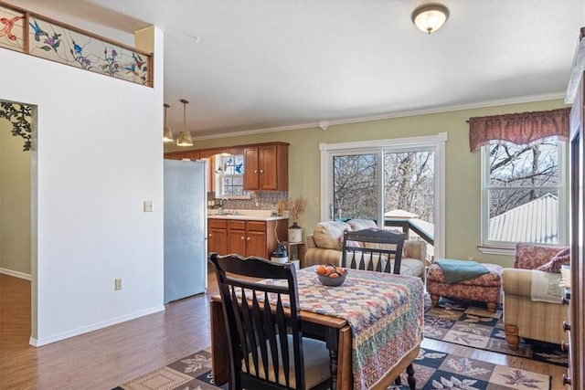 dining space featuring baseboards, wood finished floors, and ornamental molding