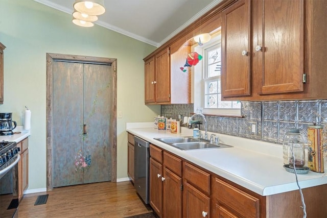 kitchen with gas range, stainless steel dishwasher, brown cabinets, and a sink