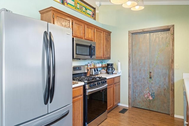 kitchen featuring brown cabinetry, visible vents, light wood finished floors, light countertops, and appliances with stainless steel finishes