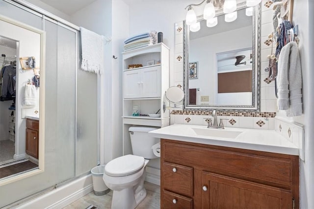 bathroom featuring backsplash, a stall shower, vanity, and toilet