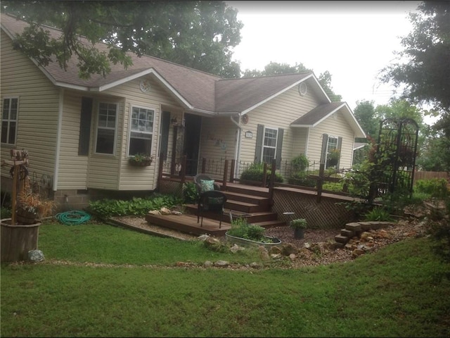 rear view of property with a deck, a lawn, and a shingled roof