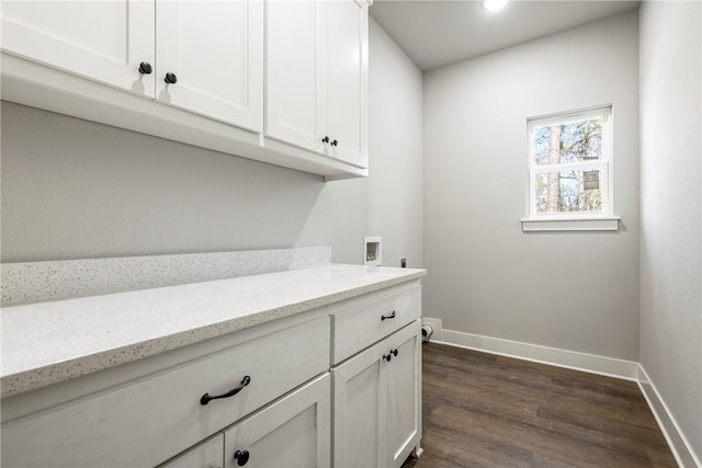 washroom with dark wood finished floors, cabinet space, hookup for a washing machine, and baseboards