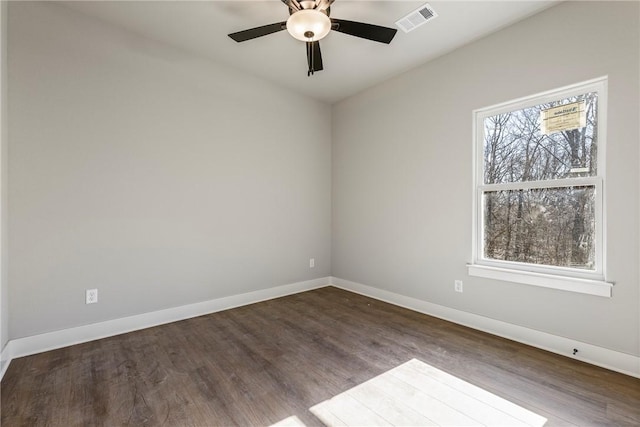 spare room featuring visible vents, ceiling fan, baseboards, and dark wood-style flooring