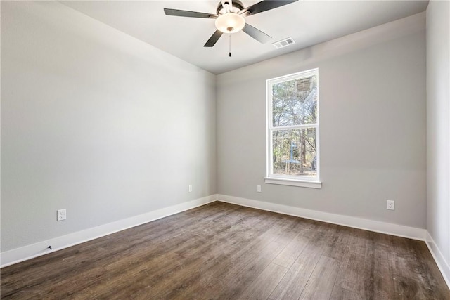 empty room featuring visible vents, baseboards, dark wood-type flooring, and ceiling fan