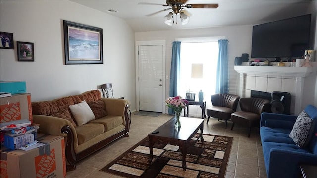 living room featuring light tile patterned floors, visible vents, a tile fireplace, and ceiling fan