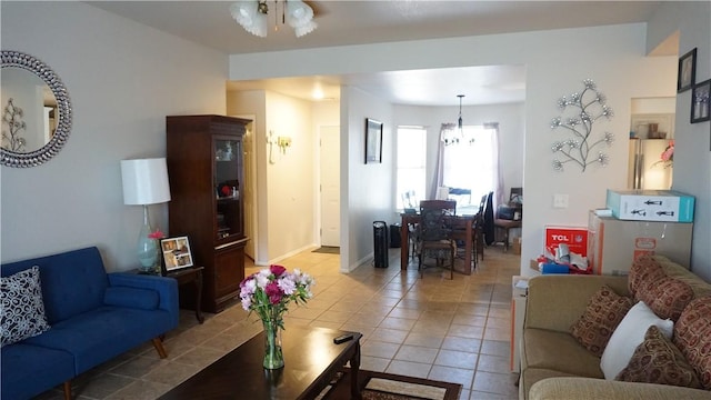 living area with an inviting chandelier, light tile patterned flooring, and baseboards