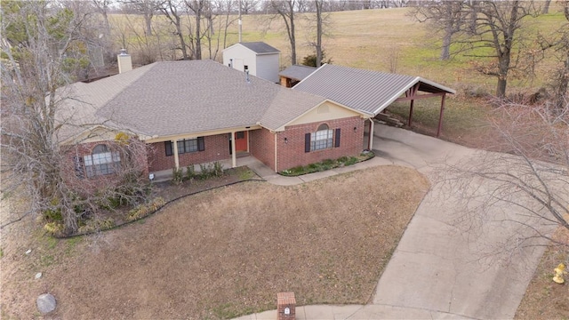 view of front of home featuring brick siding, a chimney, and concrete driveway