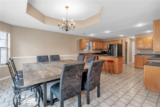 dining space with a notable chandelier, a tray ceiling, recessed lighting, light tile patterned floors, and baseboards