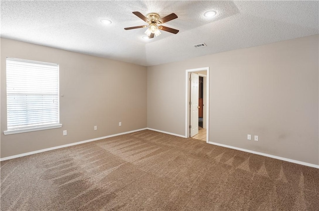 empty room featuring a ceiling fan, baseboards, visible vents, carpet floors, and a textured ceiling