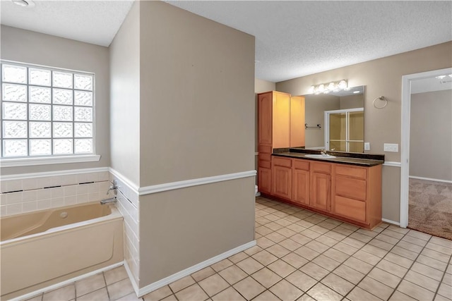 bathroom featuring vanity, tile patterned flooring, a shower stall, a textured ceiling, and a garden tub