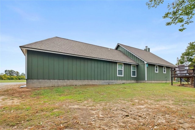 view of side of home featuring a lawn and roof with shingles