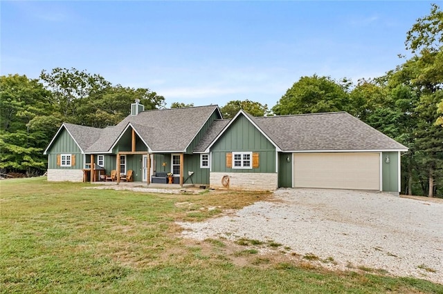 view of front of property with board and batten siding, gravel driveway, a front lawn, roof with shingles, and an attached garage