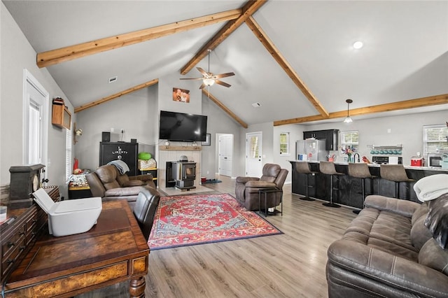 living area featuring a ceiling fan, beamed ceiling, wood finished floors, and high vaulted ceiling