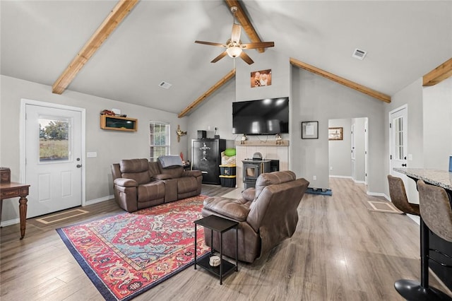 living room with beam ceiling, visible vents, a ceiling fan, and light wood-style floors