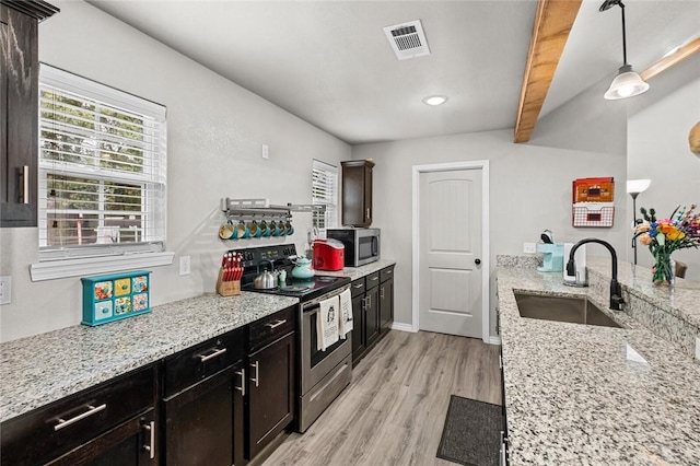 kitchen with visible vents, a sink, appliances with stainless steel finishes, light wood finished floors, and light stone countertops