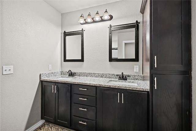 full bath featuring a sink, baseboards, and double vanity