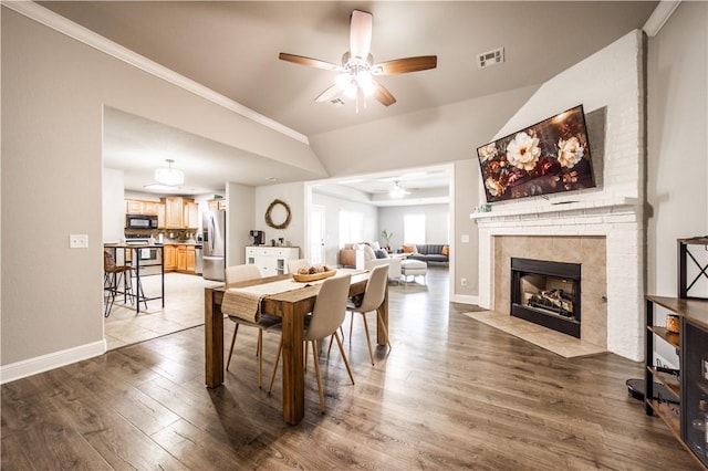 dining area featuring visible vents, a tile fireplace, baseboards, and wood finished floors