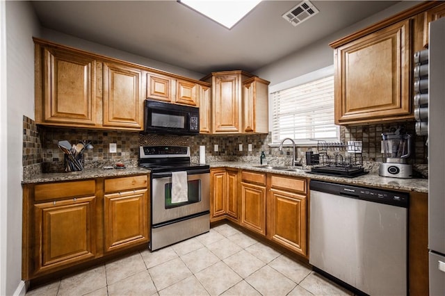 kitchen with visible vents, light stone countertops, decorative backsplash, appliances with stainless steel finishes, and a sink