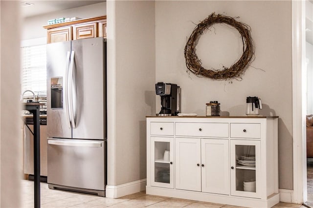 kitchen with light tile patterned floors, glass insert cabinets, baseboards, and stainless steel fridge with ice dispenser