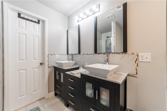 bathroom featuring tile patterned flooring, double vanity, walk in shower, and a sink