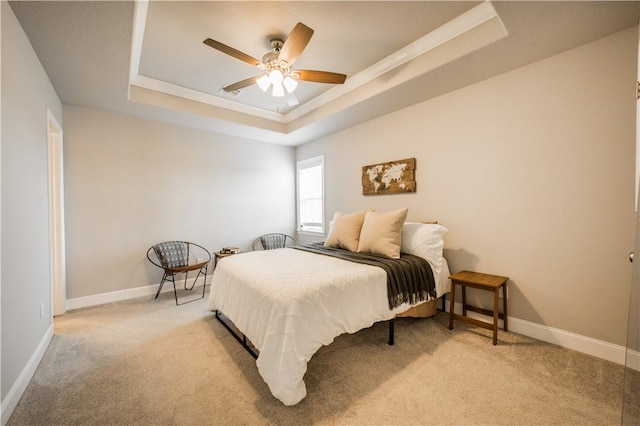 bedroom featuring a tray ceiling, carpet flooring, crown molding, and baseboards