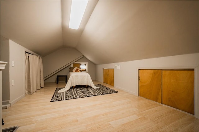 unfurnished bedroom featuring vaulted ceiling, baseboards, and wood finished floors