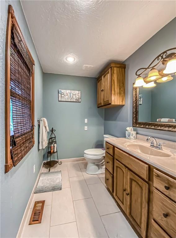 bathroom featuring tile patterned flooring, visible vents, baseboards, toilet, and vanity