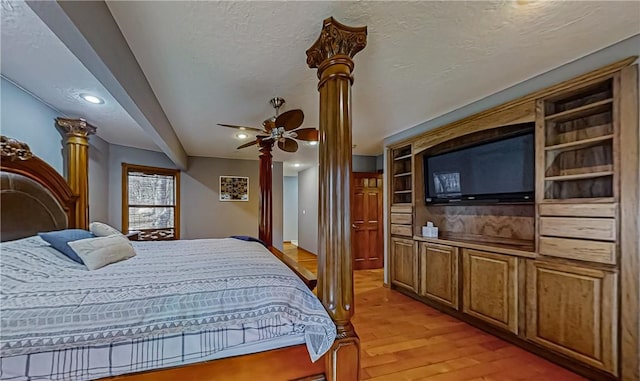 bedroom with recessed lighting, decorative columns, light wood-style floors, and a textured ceiling