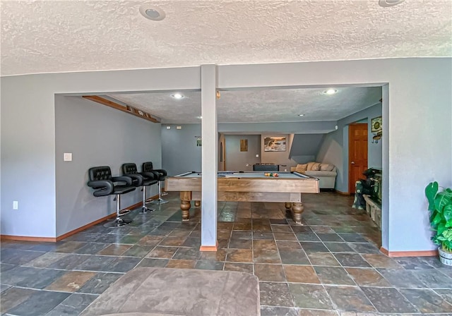 playroom with billiards, stone finish flooring, baseboards, and a textured ceiling