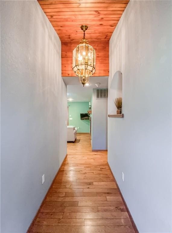 hallway featuring visible vents, an inviting chandelier, wood ceiling, and light wood-style floors