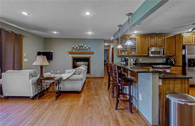 kitchen with open floor plan, brown cabinets, stainless steel appliances, and a kitchen bar