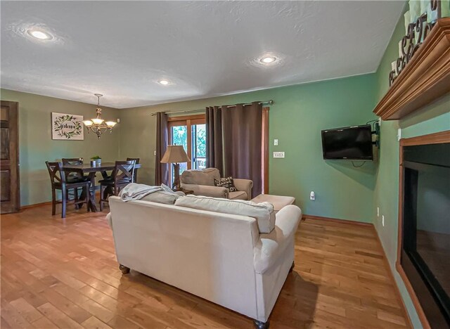 living room featuring recessed lighting, light wood-type flooring, baseboards, and a chandelier