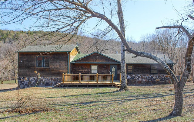 rear view of property featuring a deck, a yard, and a shingled roof