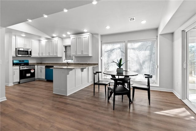 kitchen with visible vents, a peninsula, vaulted ceiling, appliances with stainless steel finishes, and dark countertops