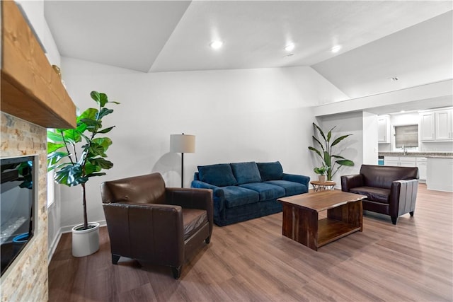 living room with recessed lighting, lofted ceiling, wood finished floors, and a fireplace