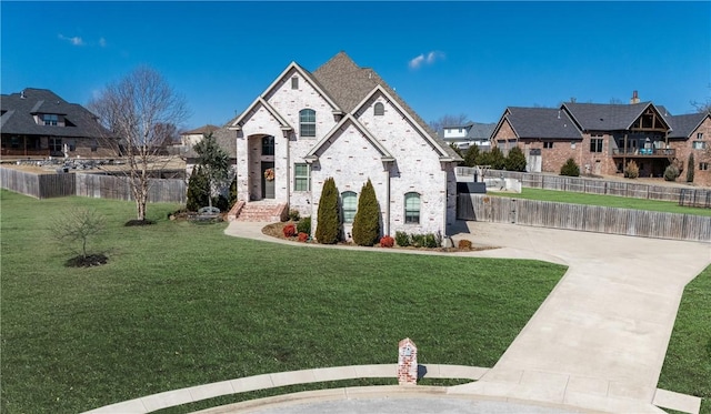 french country inspired facade featuring a residential view, a front lawn, and fence