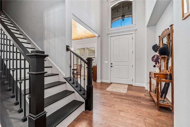 foyer featuring hardwood / wood-style floors, a high ceiling, stairs, and baseboards