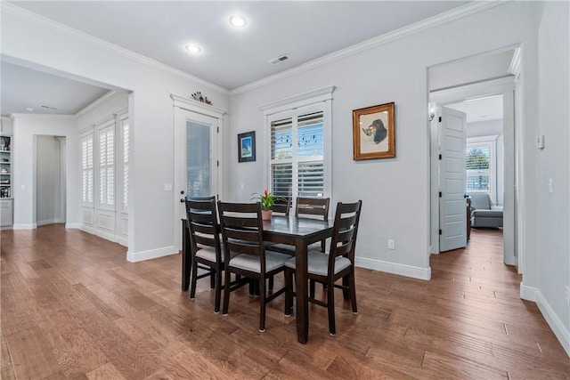 dining space featuring visible vents, crown molding, baseboards, and wood finished floors