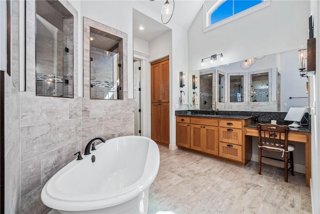 bathroom with a freestanding tub, high vaulted ceiling, a stall shower, tile walls, and vanity