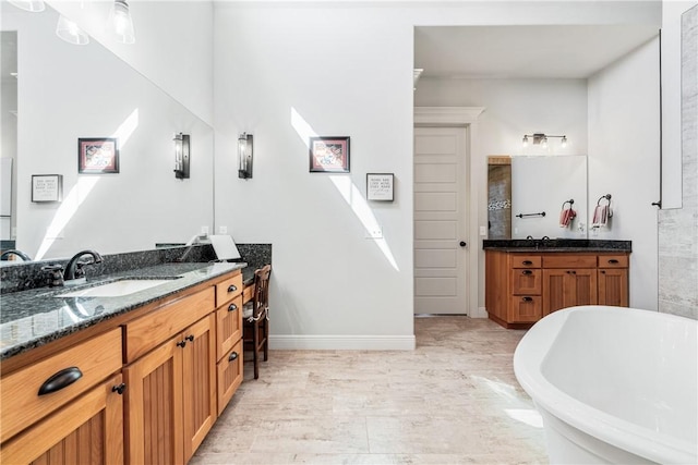 full bath with a soaking tub, two vanities, baseboards, and a sink