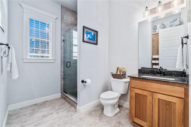 bathroom featuring a stall shower, toilet, vanity, and baseboards