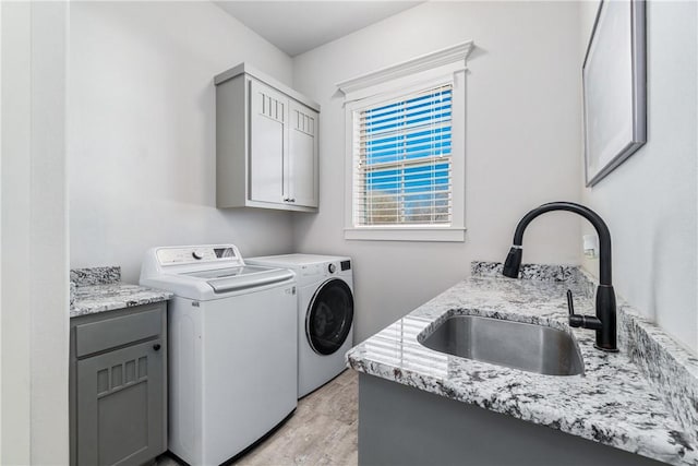 laundry area featuring washer and dryer, cabinet space, and a sink