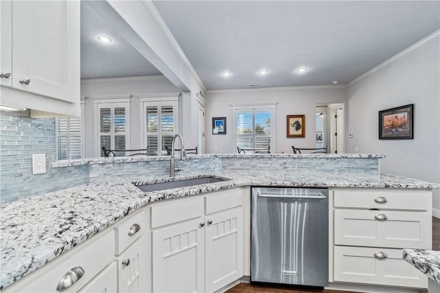 kitchen featuring stainless steel dishwasher, white cabinets, backsplash, and a sink