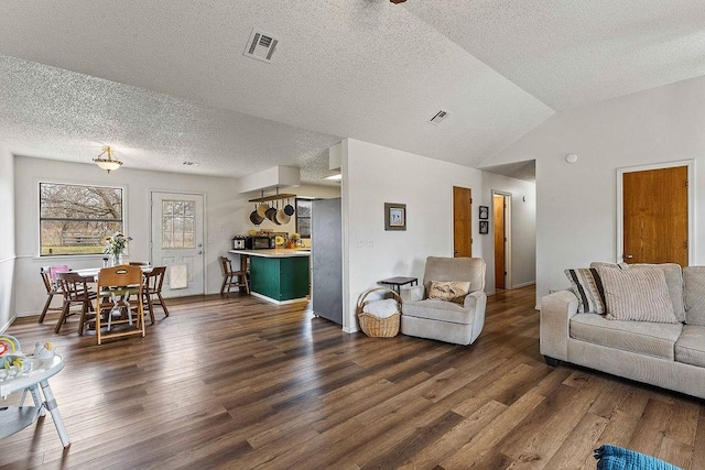 living room featuring dark wood finished floors, visible vents, a textured ceiling, and lofted ceiling