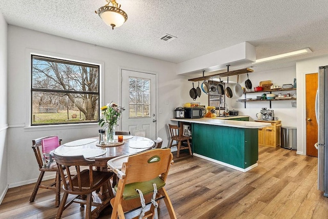 kitchen featuring light wood finished floors, visible vents, baseboards, a peninsula, and open shelves