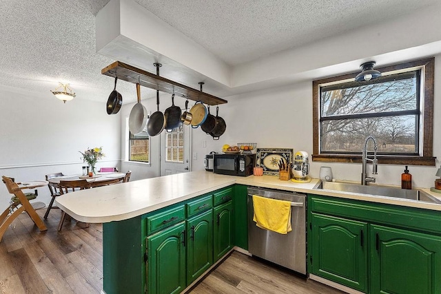 kitchen with light wood-style flooring, a sink, stainless steel dishwasher, a peninsula, and light countertops